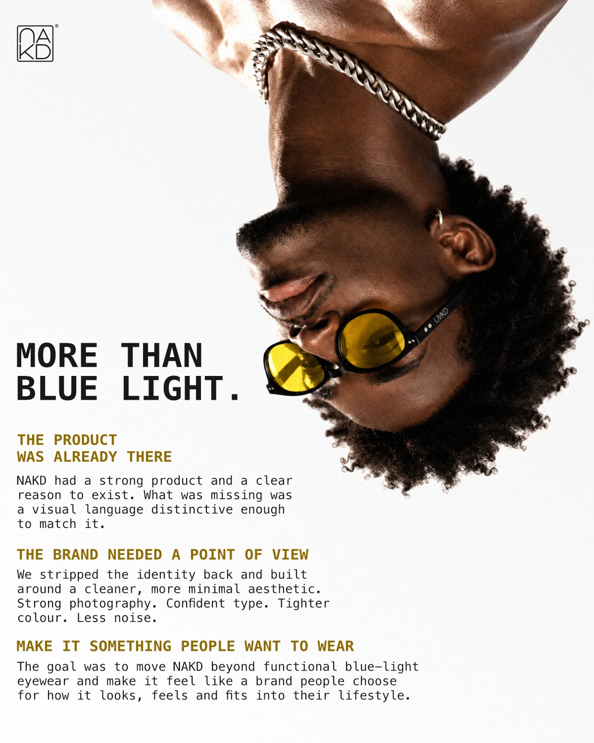Upside-down portrait wearing yellow-lens eyewear, balancing the companion red campaign poster.